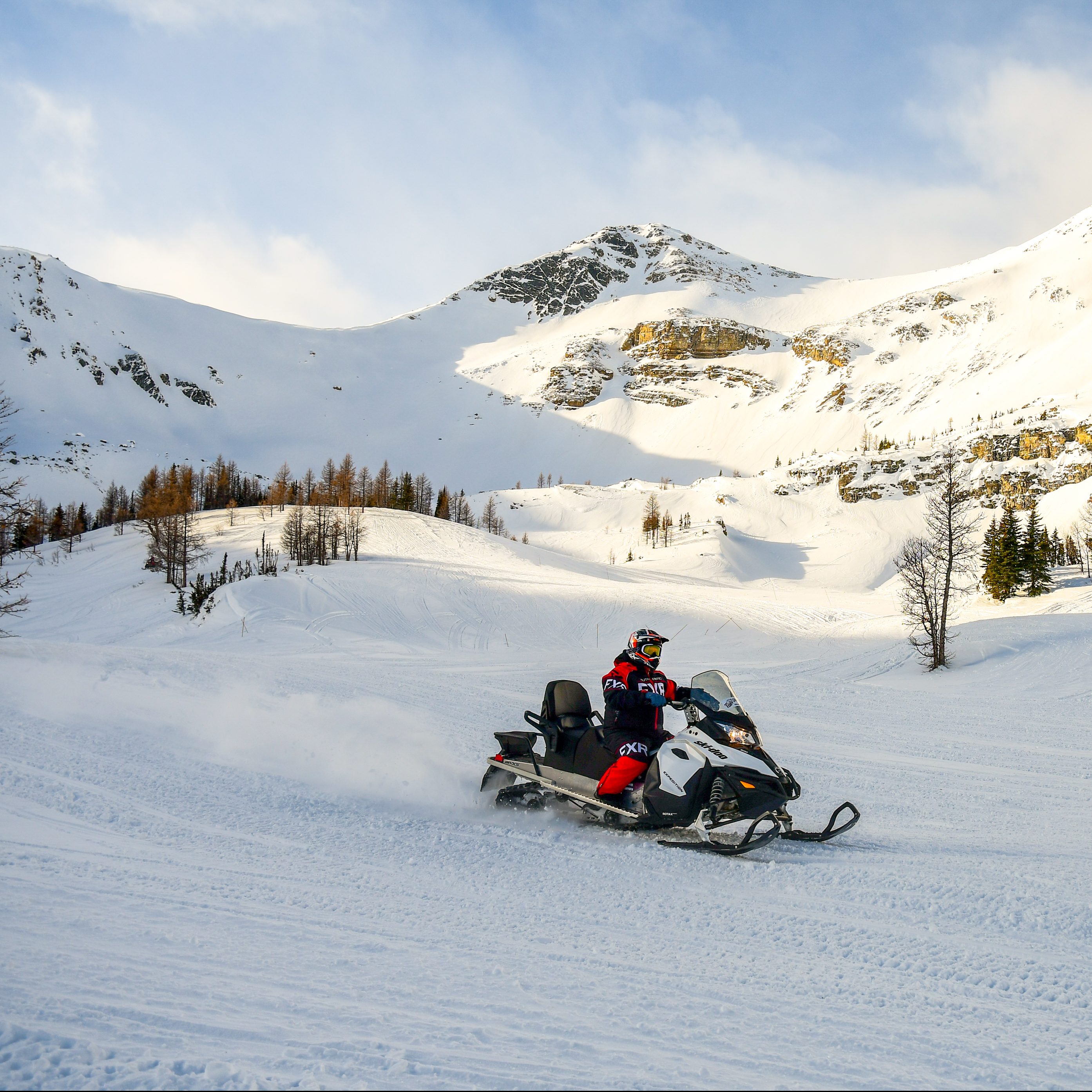 Lone snowmobiler riding across a beautiful alpine bowl at Toby Creek Adventures