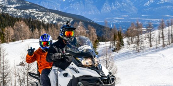 Two riders on a snowmobile tour in Paradise Basin with Toby Creek Adventures.