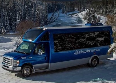 Discover Banff Tour Bus parked in front of a beautiful mountain creek