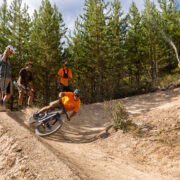 Mountain biker riding a berm with the trail crew having fun and watching