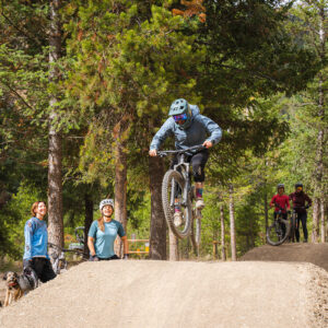 Mountain bike rider jumping in the skills park with people watching