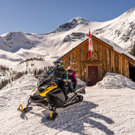 Snowmobile infront of the Paradise Cabin with child
