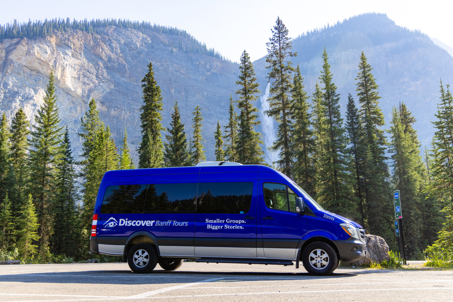 A Discover Banff Tour Bus Infront of a majestic waterfall